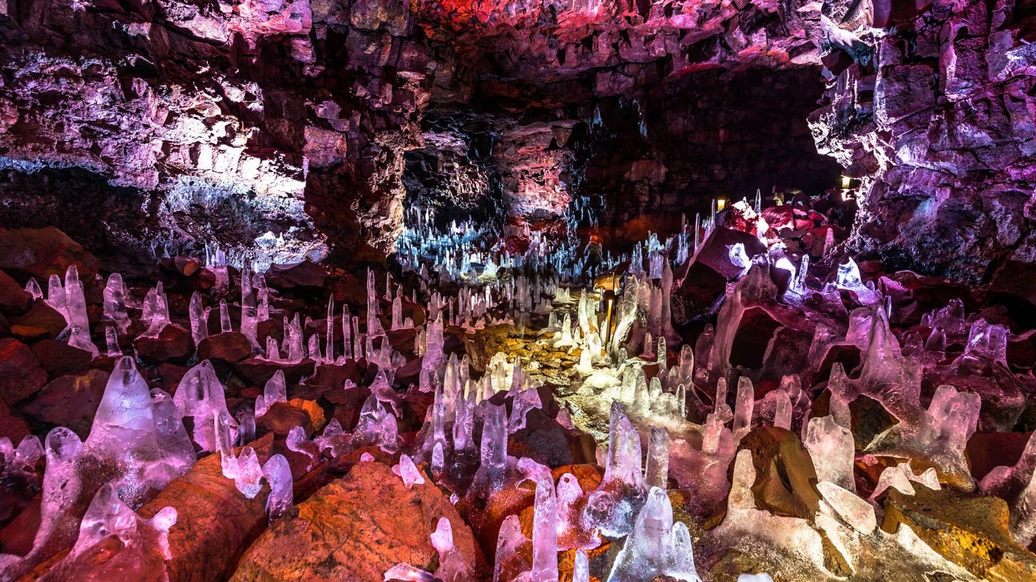 Alt Text: The colourful interior of the Raufarhólshellir lava tube in Iceland. 