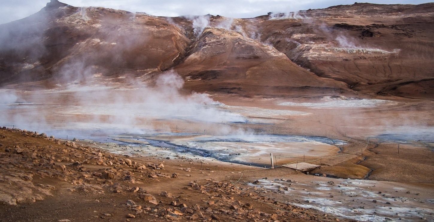 Area of geothermally heated springs in a red-coloured Iceland landscape.