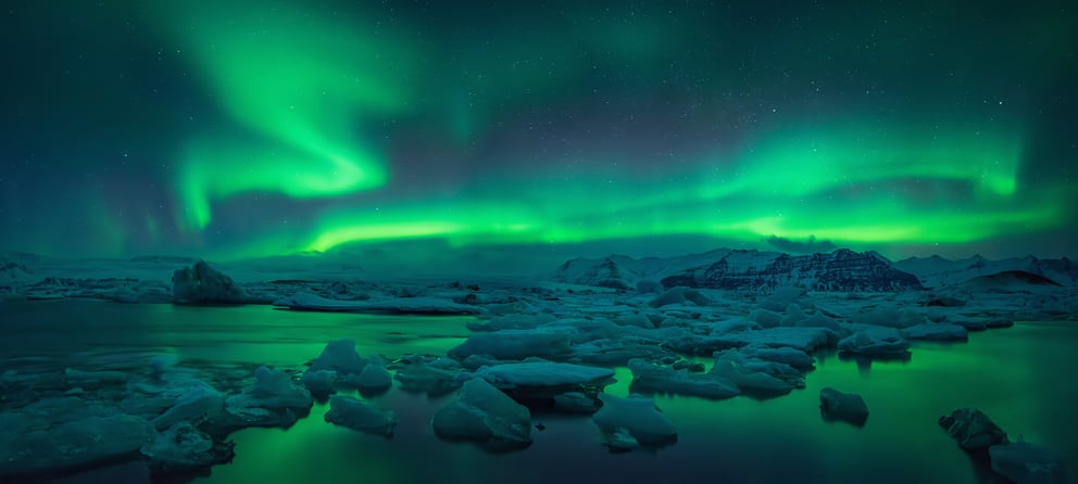 Green northern lights and icebergs in Iceland.