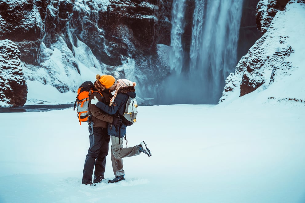 Couple kissing at Skogarfoss waterfall in winter.