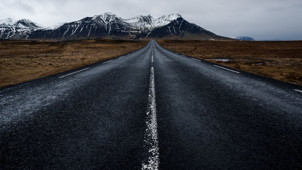 Open road in Iceland heading towards snow-capped mountains.