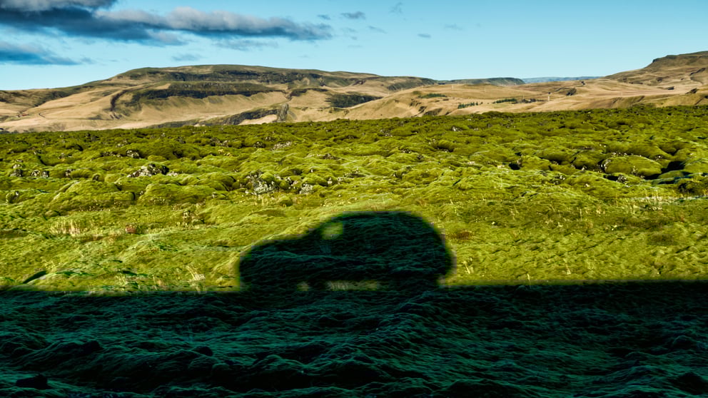 Shadow of a car driving through the Icelandic landscape.