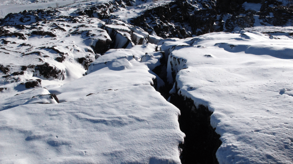 A crack in the snow-covered ground in Thingvellir National Park.