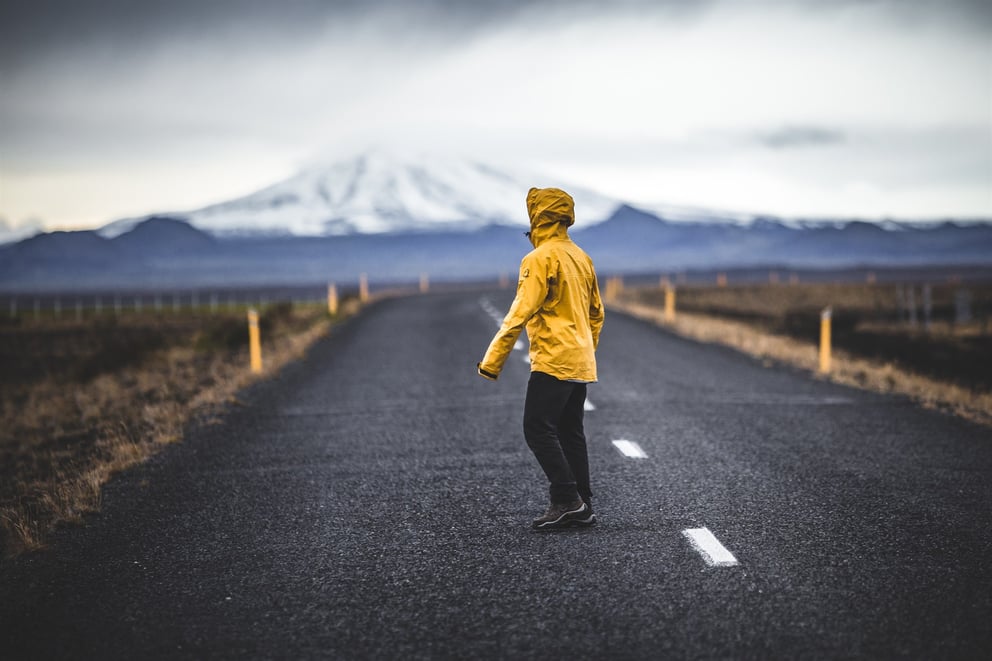 Person standing on a road in Iceland in a yellow rain jacket. 