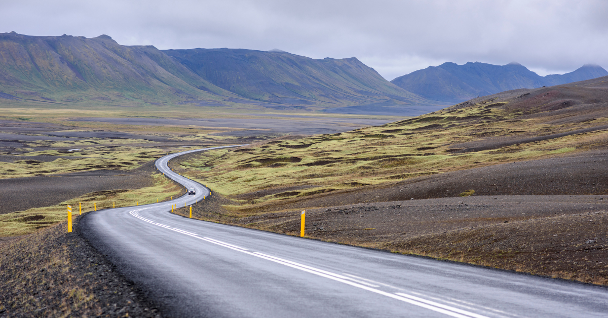 Winding tarmac of Iceland’s Route 1 through the rocky, moss-covered landscape.