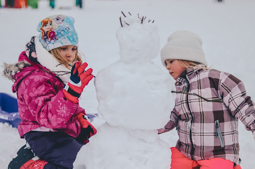 Two young children making a snowman