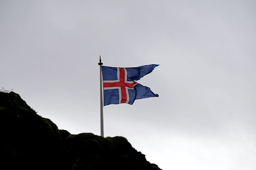 Icelandic flag on a mountain waving against a grey sky
