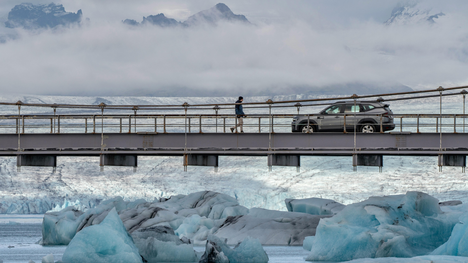 Man walking back to his car across a bridge in Iceland.