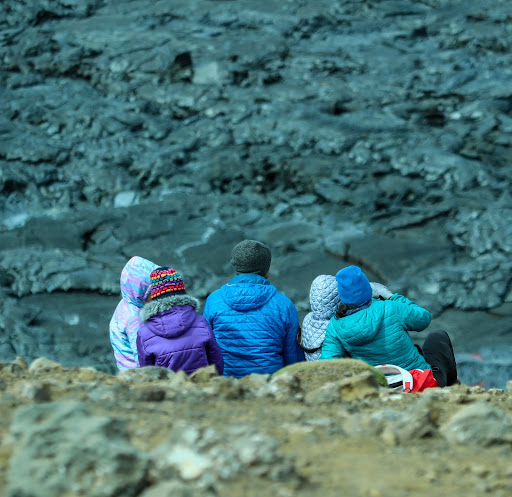 Kids with parents sat on a volcanic lava field in Iceland