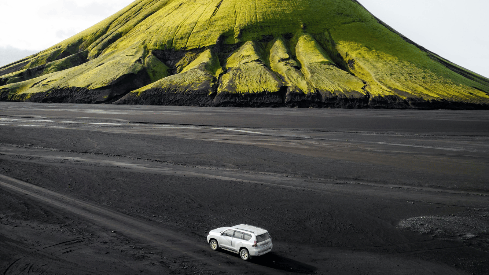 Car driving across black sand beach in Iceland.