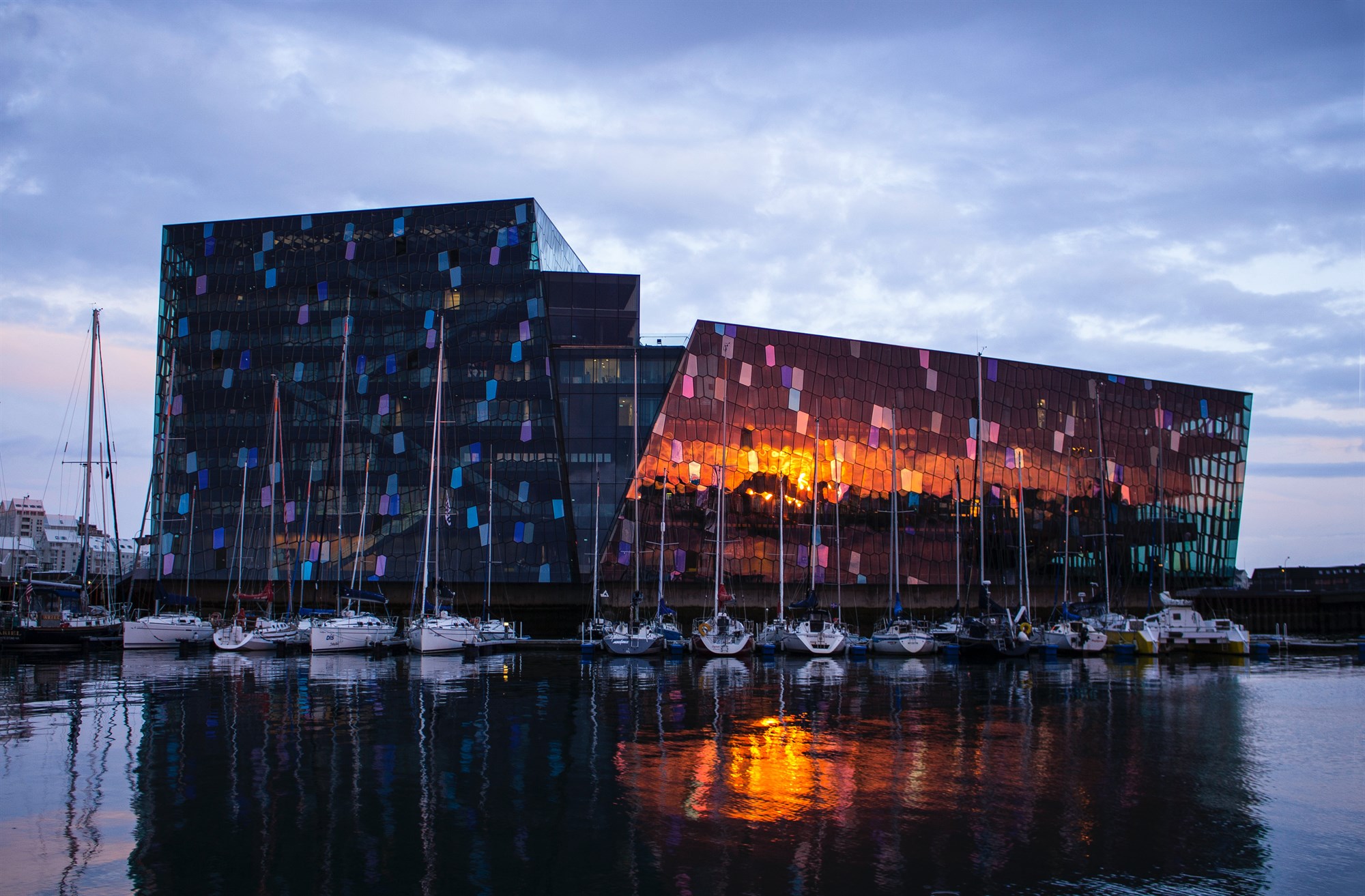 Harpa Concert Hall in Iceland at dusk, surrounded by sailing boats 