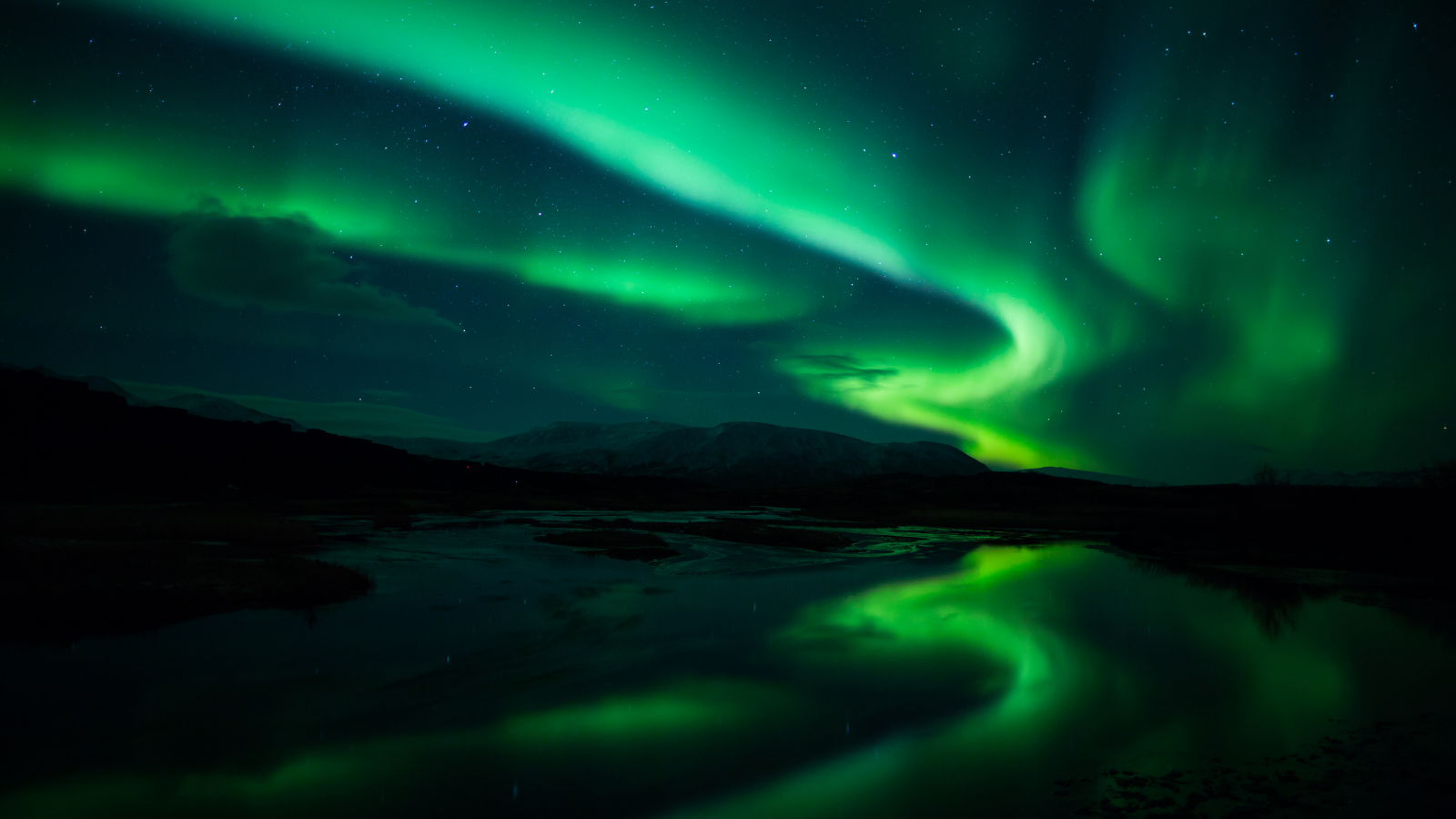 Green aurora borealis over mountain landscape in Iceland.