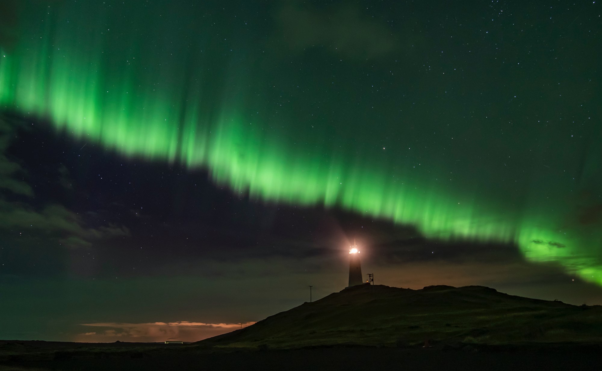 Northern Lights visible over a lighthouse in Iceland