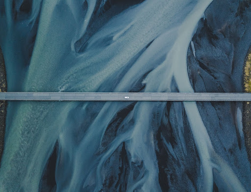 Aerial shot of a car on a bridge over a river in Iceland.