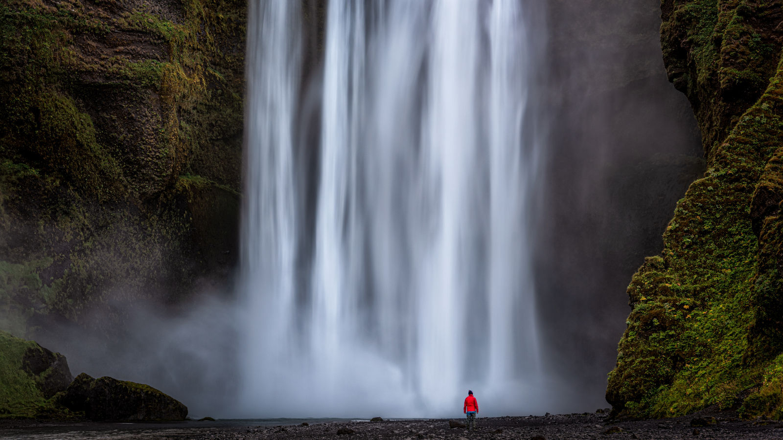 Person standing at the base of Skógafoss.