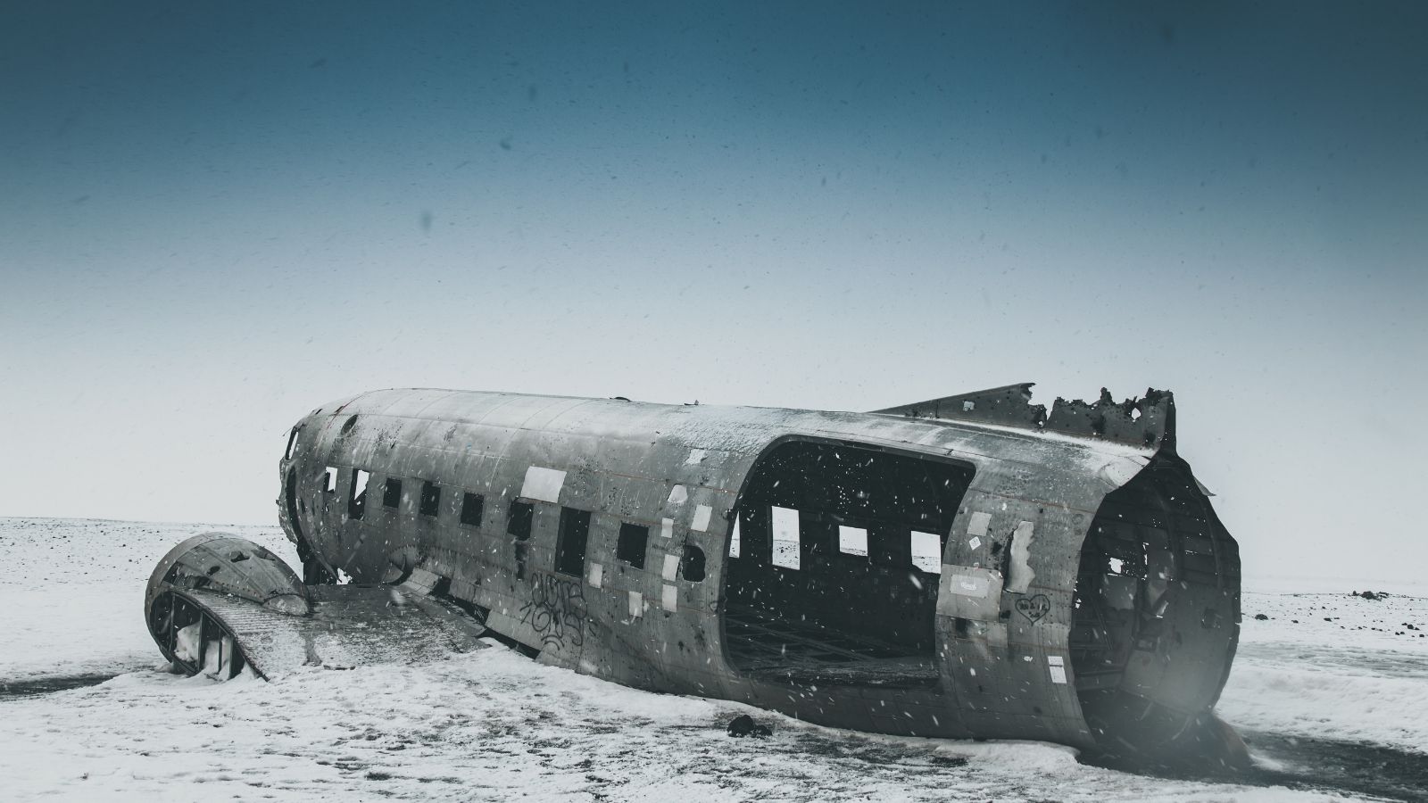 Sólheimasandur plane wreck surrounded by snow on a clear day