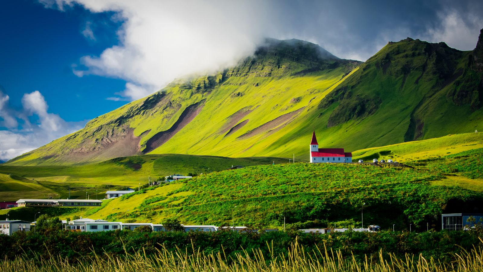 Church against green mountains in Iceland during the summer.