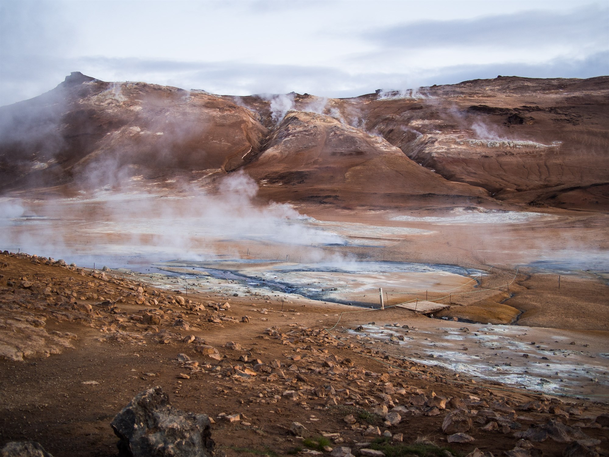 Area of geothermally heated springs in a red-coloured Iceland landscape.