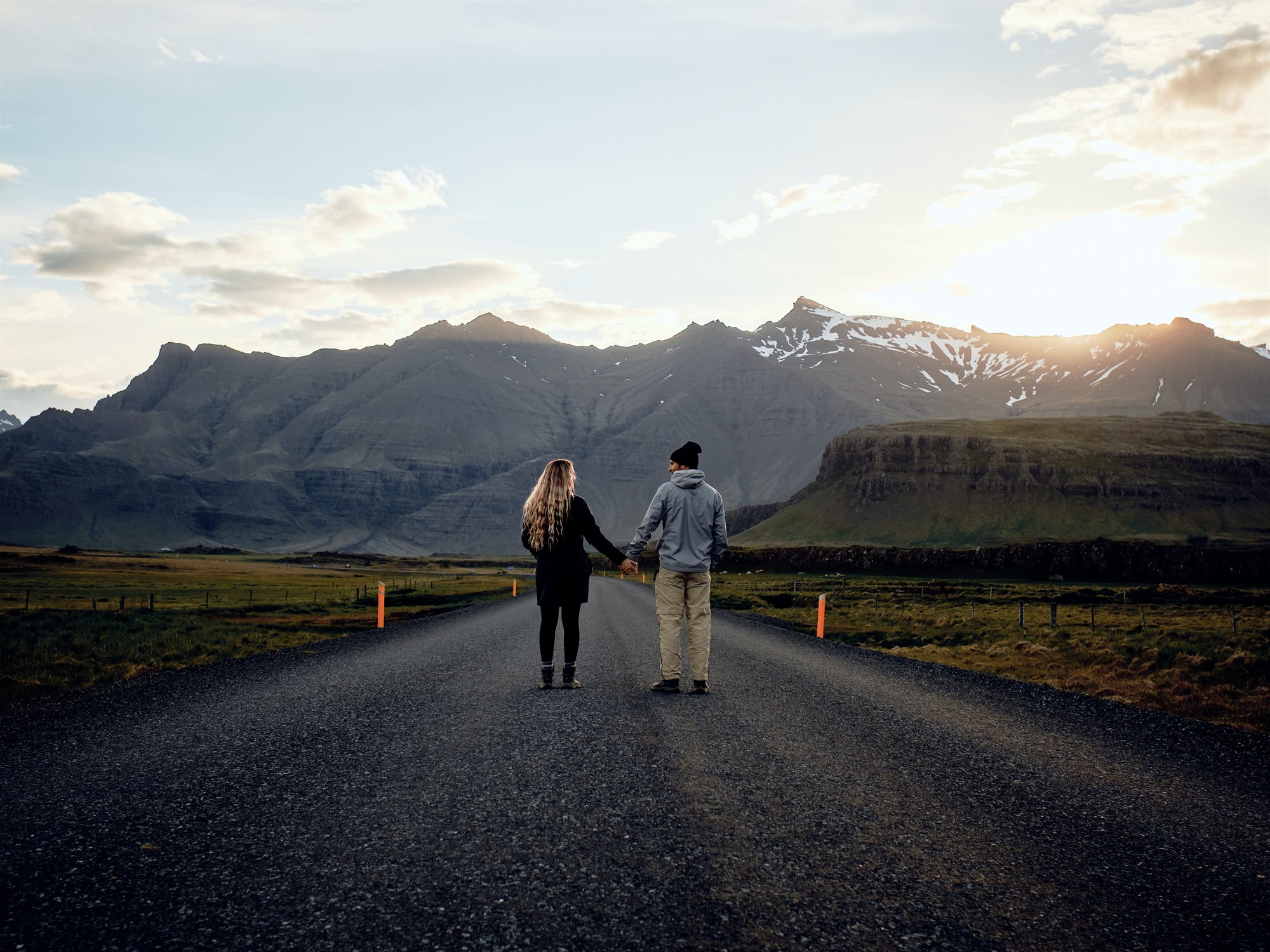 Travel blogger couple standing holding hands on the Ring Road in Iceland.