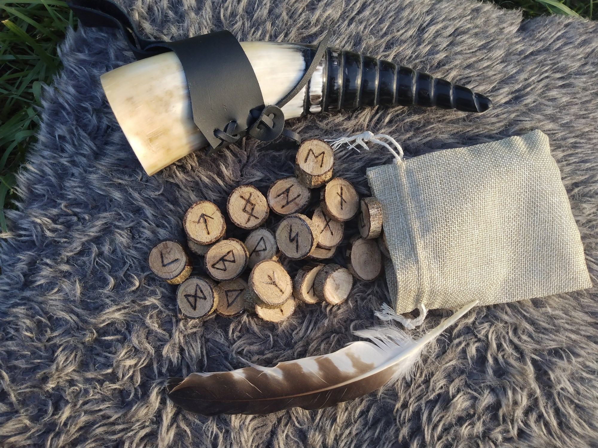 Viking drinking horn with a set of wooden Elder Futhark rune tiles and a feather. 